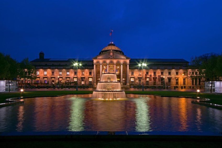 En storslået bygning med en central fontæne om natten. 1