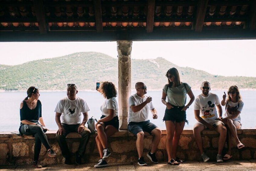 Un gruppo di persone sedute su una pietra che si affaccia su un lago e delle colline. 3