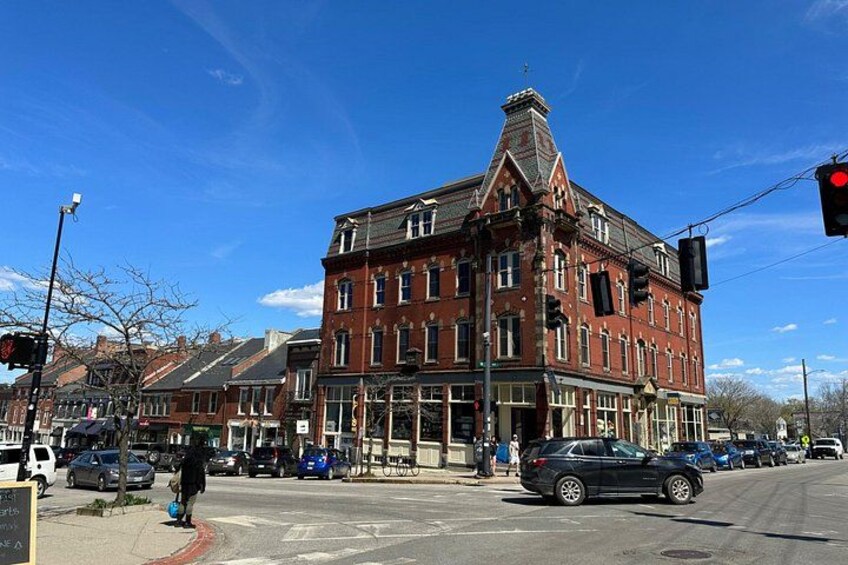 A red brick building with a corner entrance, a street intersection, and a clear blue sky. 2