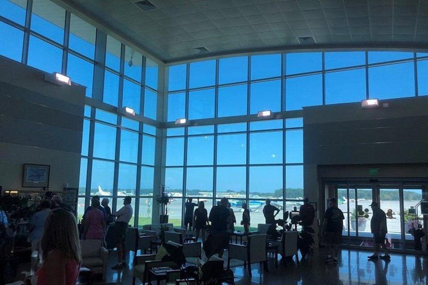 A spacious indoor area with large windows overlooking a body of water and a distant airplane. 5
