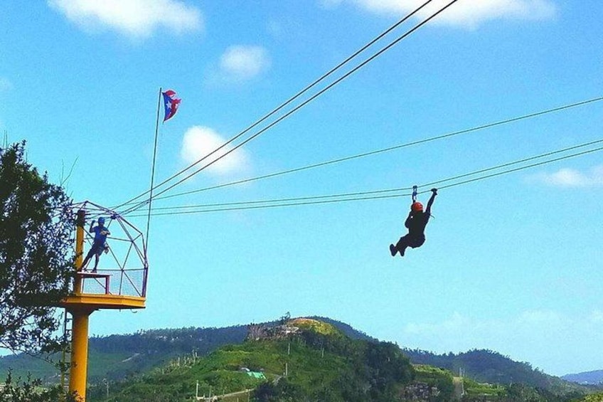 A person zip-lining over a mountainous landscape with a flag and a control tower. 5
