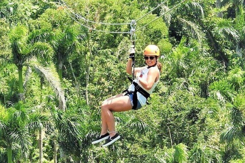 A person zip-lining through a dense, tropical forest. 1