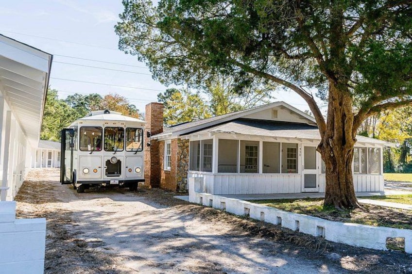 Un autobús blanco estacionado frente a una casa con un árbol grande. 2