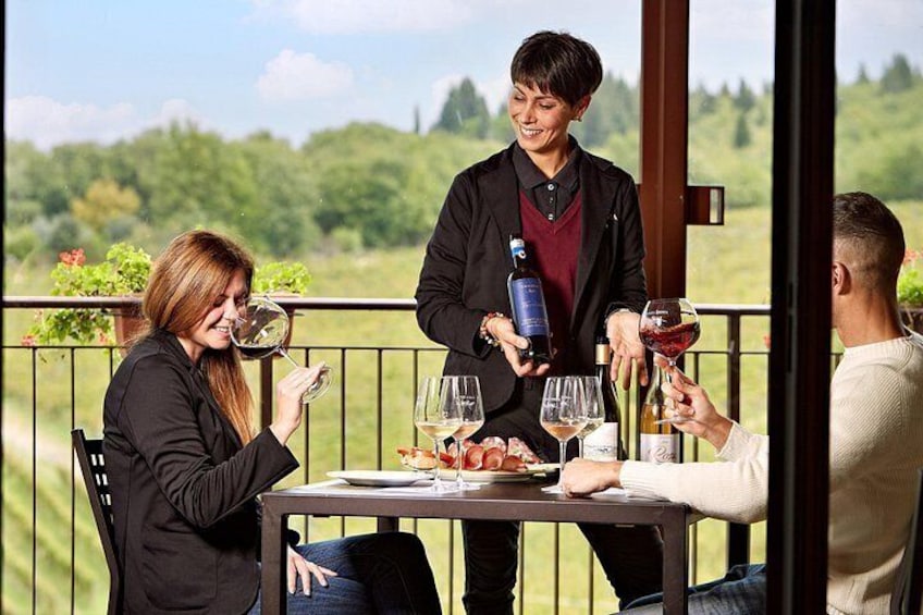 Una persona sirviendo vino en una copa, sentada en una mesa al aire libre con vistas panorámicas. 1