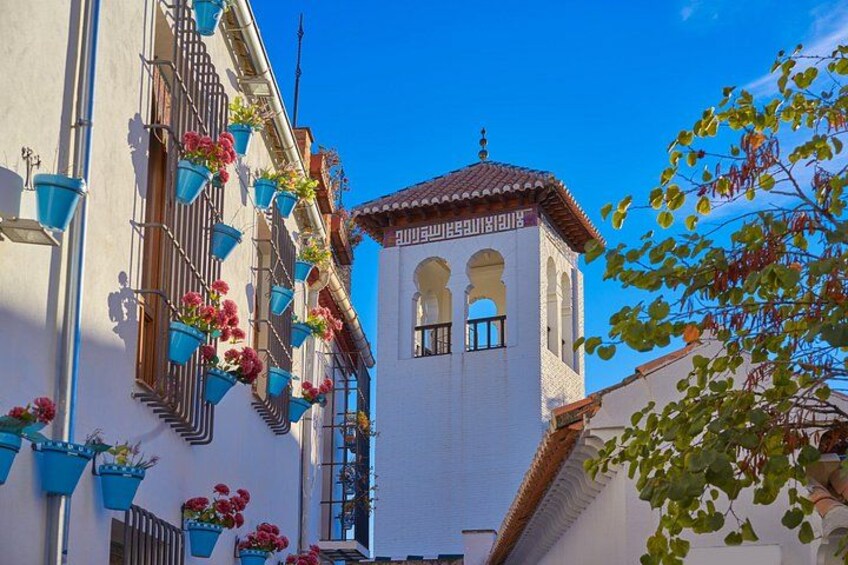 Un edificio con un campanario, macetas colgantes de flores azules y un cielo azul despejado. 2