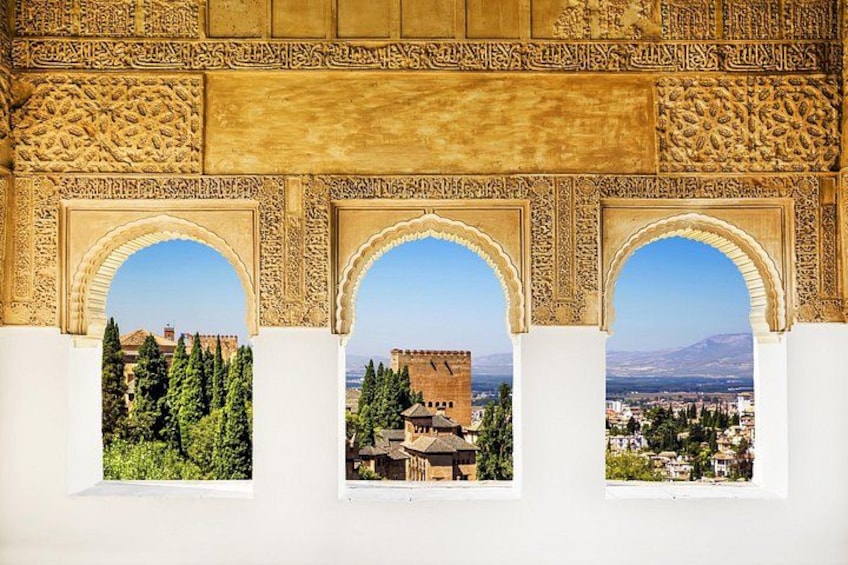 A view through ornate arches with a cityscape and mountains in the background. 2