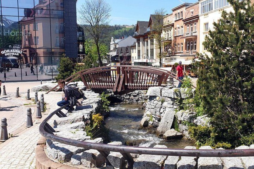 Un puente de piedra sobre un arroyo, rodeado de senderos adoquinados y follaje. 5