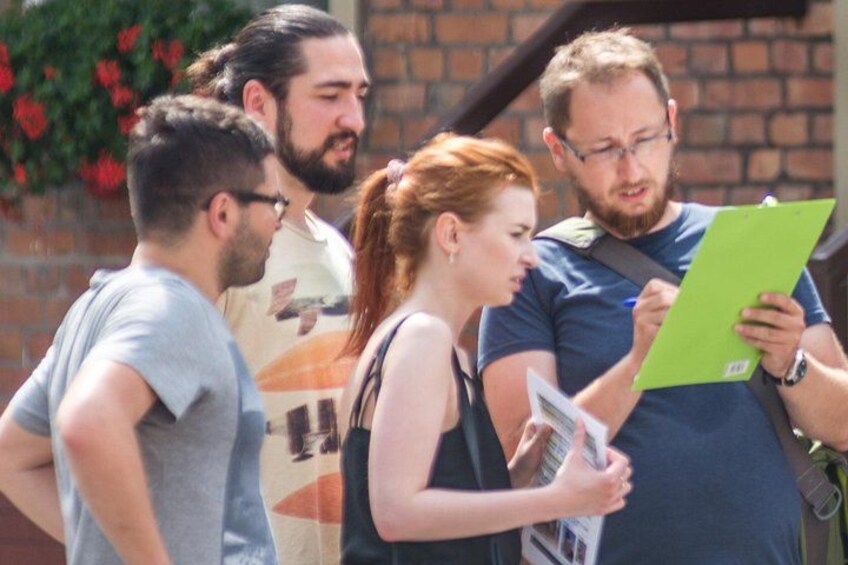 A group of people standing outdoors, some holding clipboards. 5