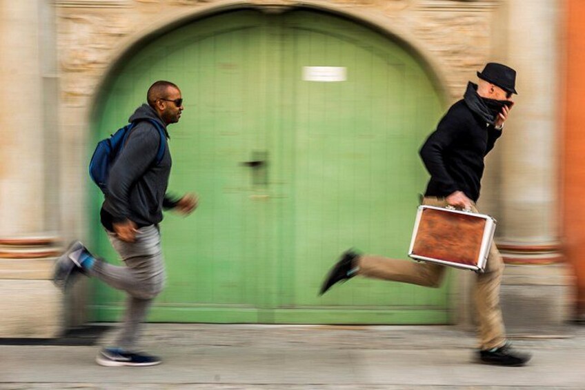 Two people running past a green door with a stone archway. 2