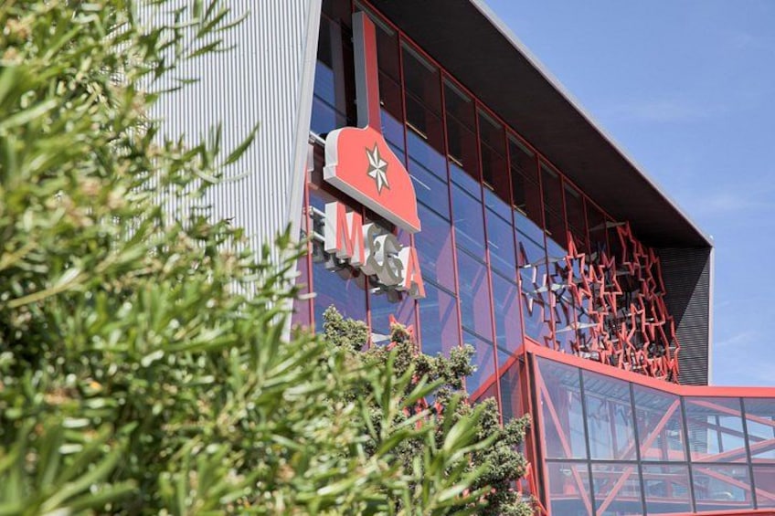 Een modern gebouw met een rood en wit bord, glazen ramen en een metalen constructie. 3