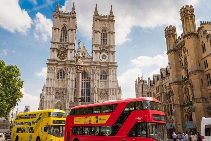 Un autobus à deux étages rouge devant un bâtiment historique doté de tours horloges. 2