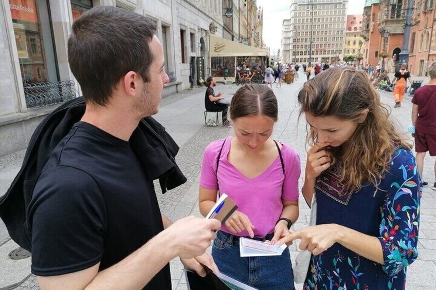Three people examining a booklet on a city street. 4