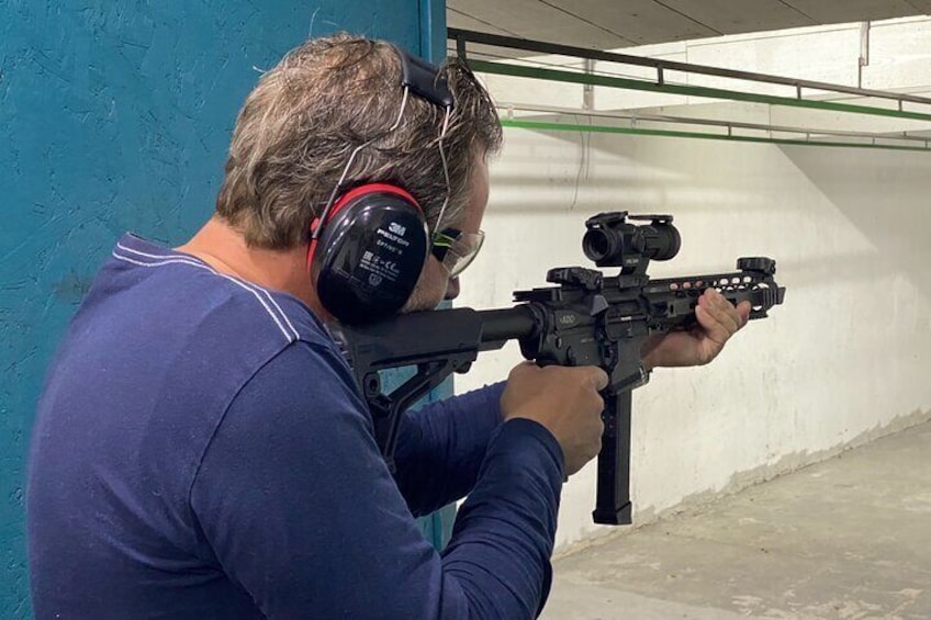 A person aiming a rifle with a scope. 2