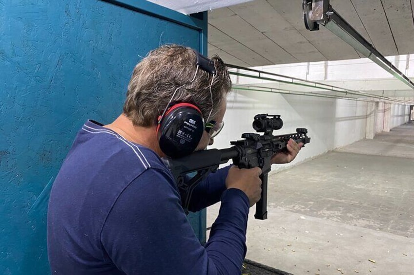 A person aiming a rifle with a scope at a shooting range. 5