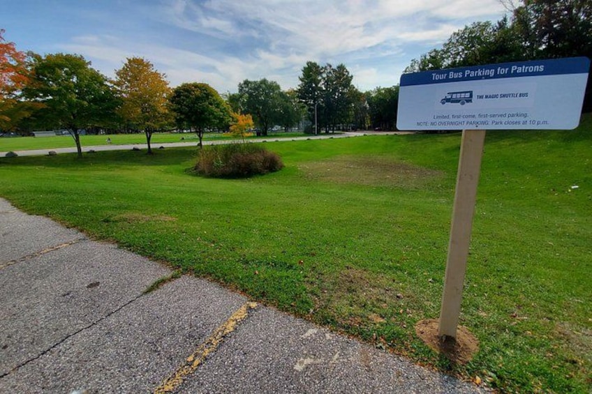 A grassy area with a sign for tour bus parking. 5