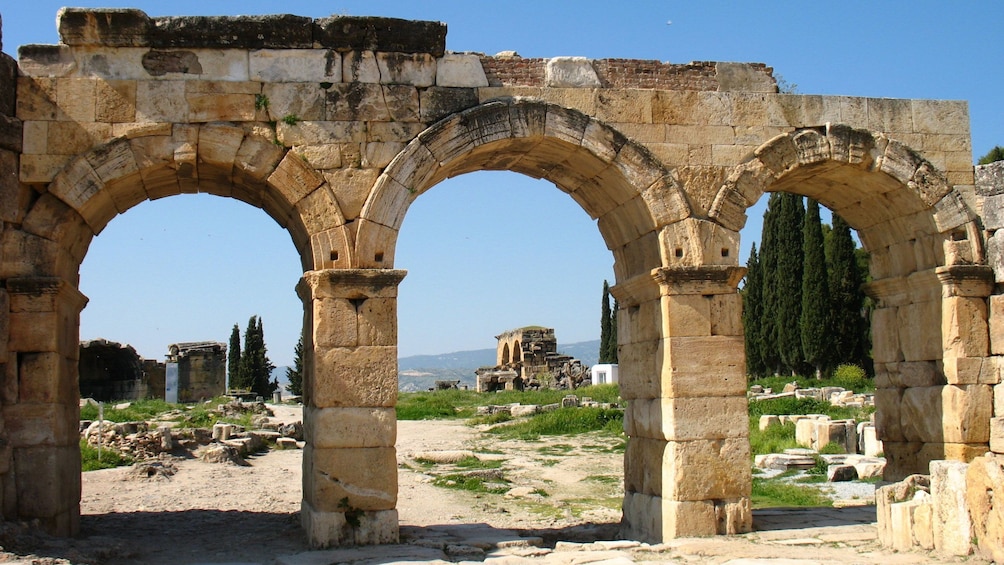 De vieilles arches en pierre, situées sur un site historique, avec des ruines en arrière-plan. 3