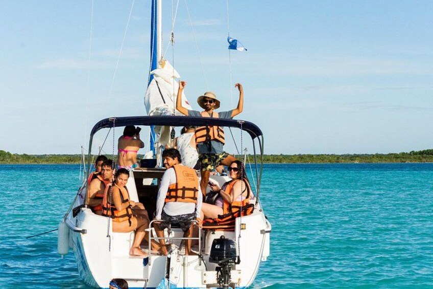 A sailboat with passengers wearing life jackets on a turquoise sea. 5