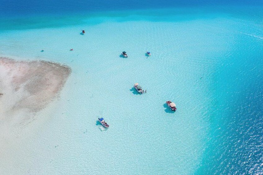 A turquoise sea with boats and a sandy beach. 3