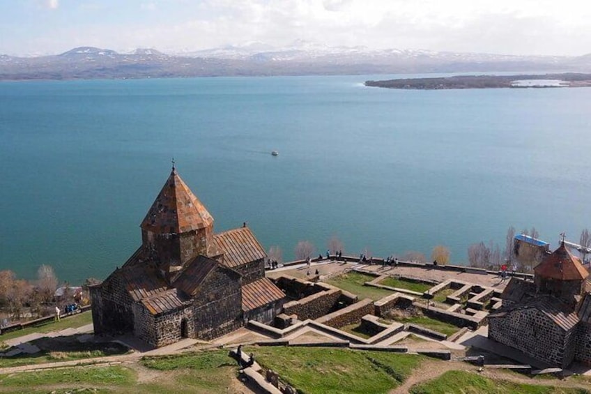 A historic church with a bell tower, a fortress, and a large body of water in the background. 5