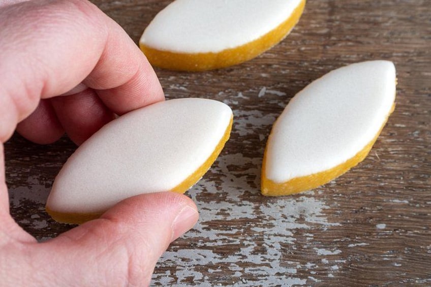Een hand houdt een witte gebakken patisserie met een goudbruine korst vast, geplaatst op een houten oppervlak met duidelijke slijtage. 2