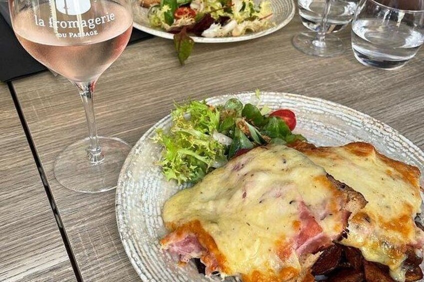 Une assiette de nourriture, un verre de vin rosé, une salade et un verre d’eau, le tout posé sur une table en bois. 4
