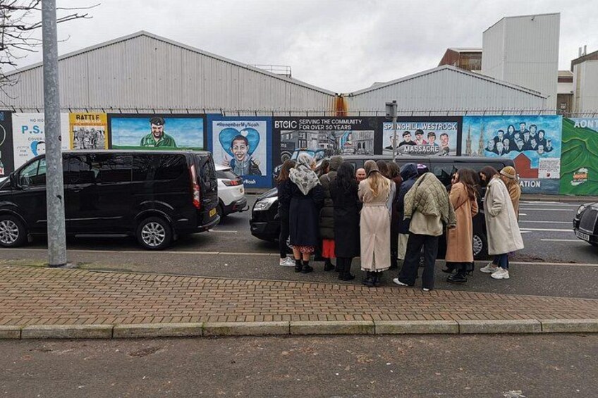 Un grupo de personas en una acera, una camioneta negra y un edificio con anuncios. 4