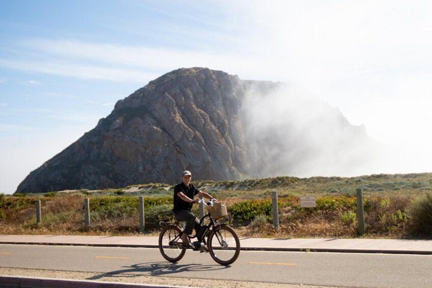 A person riding a bicycle on a road with a mountain in the background. 3