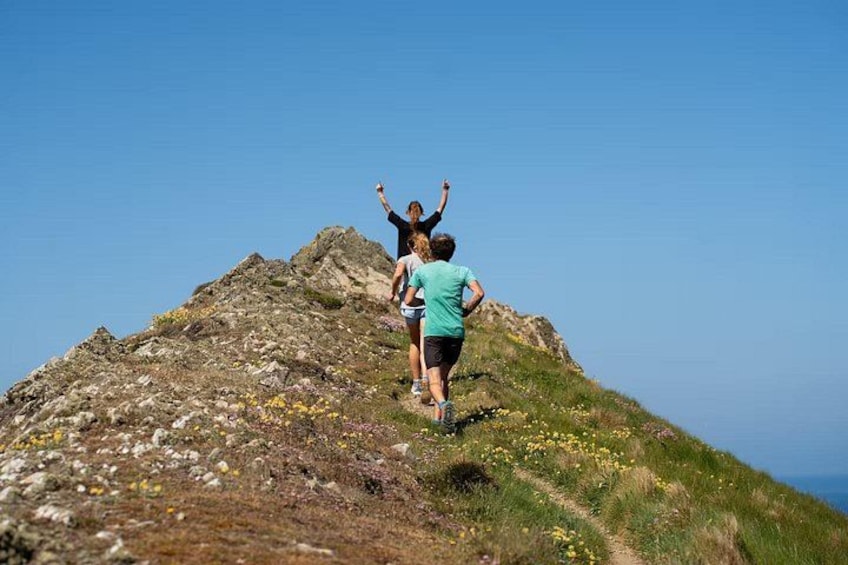 Dos personas caminando en una montaña rocosa con cielo despejado. 3