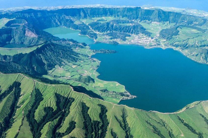 A mountainous landscape with a large lake surrounded by green fields. 4