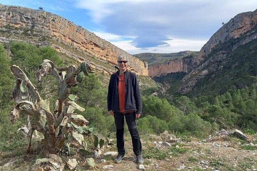 Una persona de pie en un paisaje desértico con cactus y terreno rocoso. 1