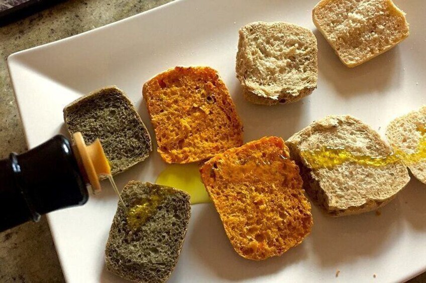 A white plate with various bread slices and a bottle of oil being poured on them. 2