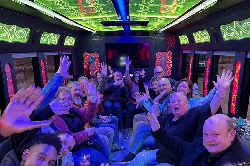 Een groep mensen in een voertuig met neonverlichting en geometrische patronen op de muren. 2