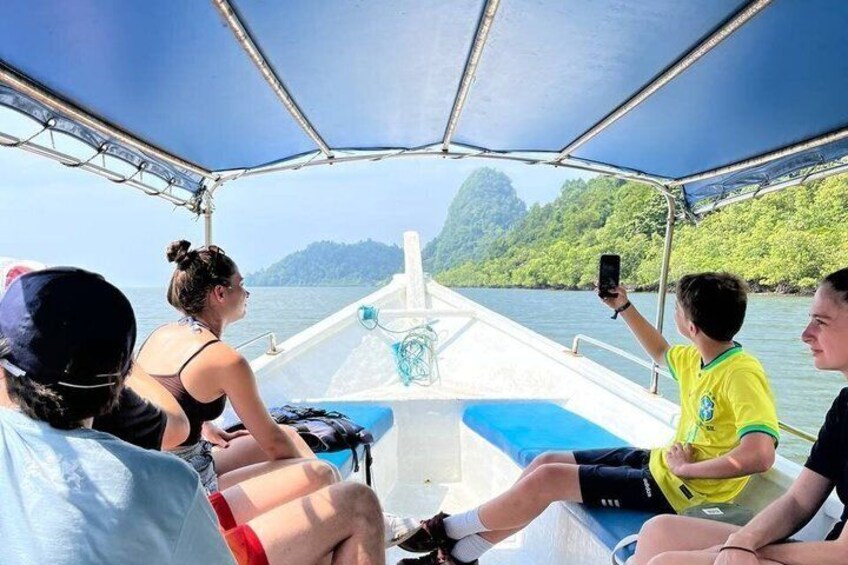 A boat with passengers, a clear sky, and a forested coastline. 2