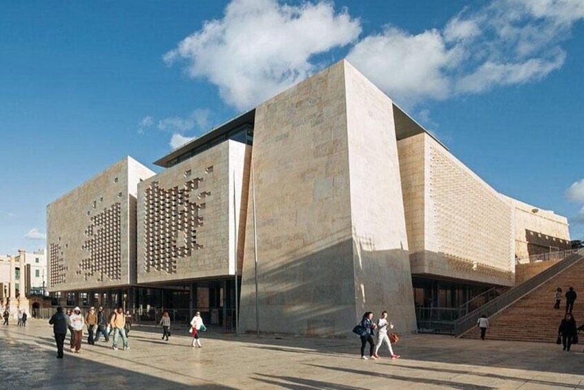 A modern building with a unique facade, a wide open plaza, and a staircase leading to the entrance. 2