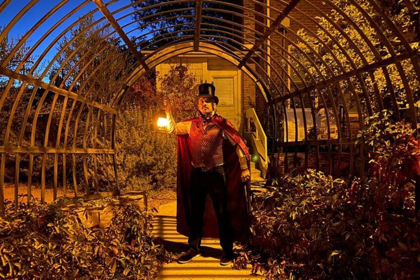 Una persona con una capa roja parada en un invernadero con plantas y una estructura metálica curva. 3