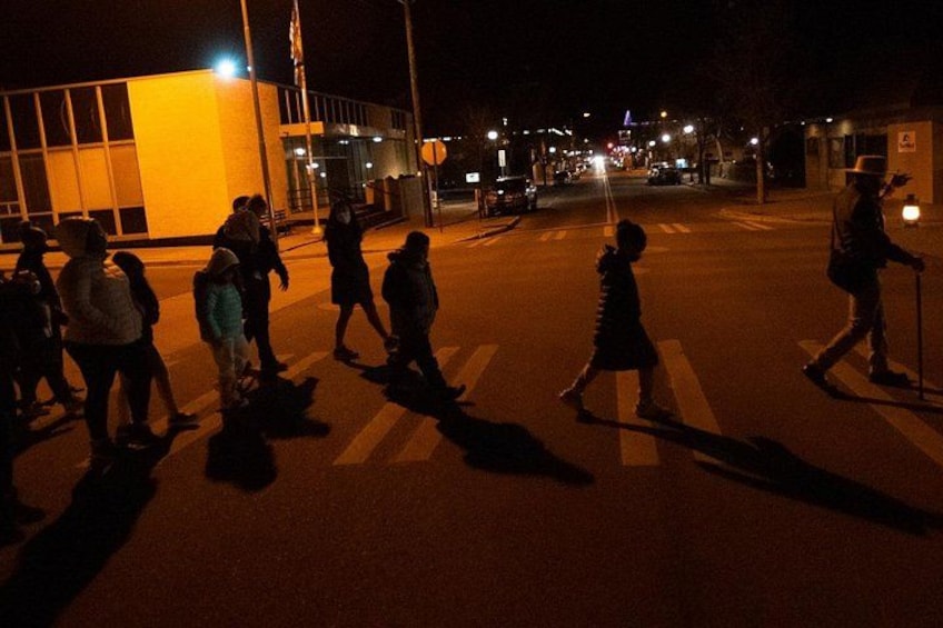 A nighttime street scene with pedestrians crossing a zebra crossing. 4