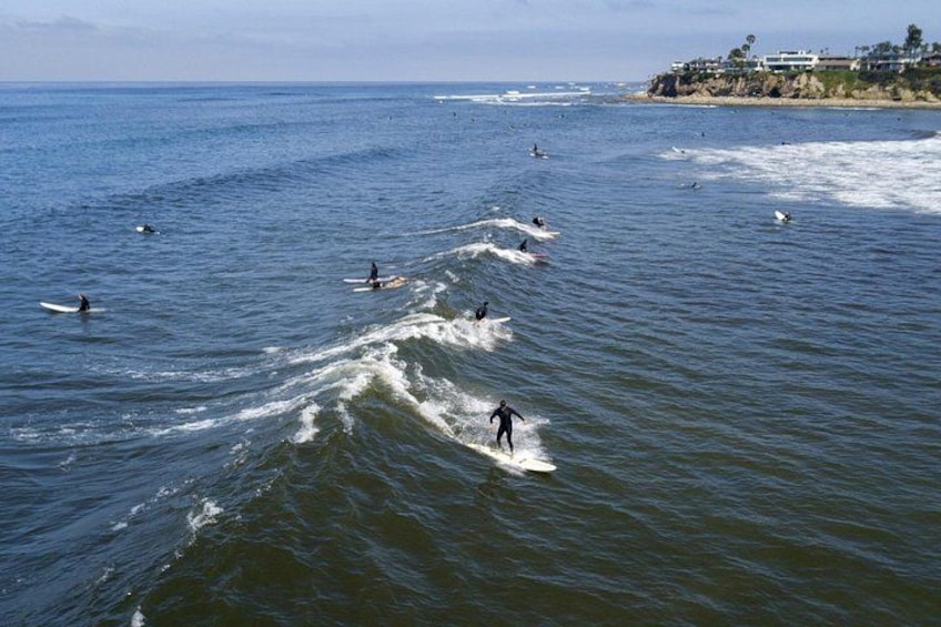 Surfistas montando olas en el océano, con una costa al fondo. 2