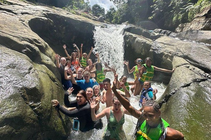 A group of people enjoying a waterfall in a rocky outdoor setting. 5