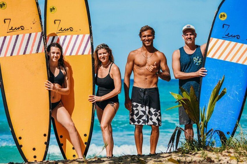 Une scène de plage où l’on voit des personnes tenant des planches de surf, avec l’océan en arrière-plan. 3