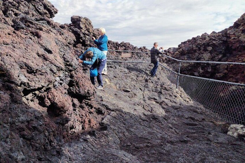 People standing on a rocky terrain with a fence. 1