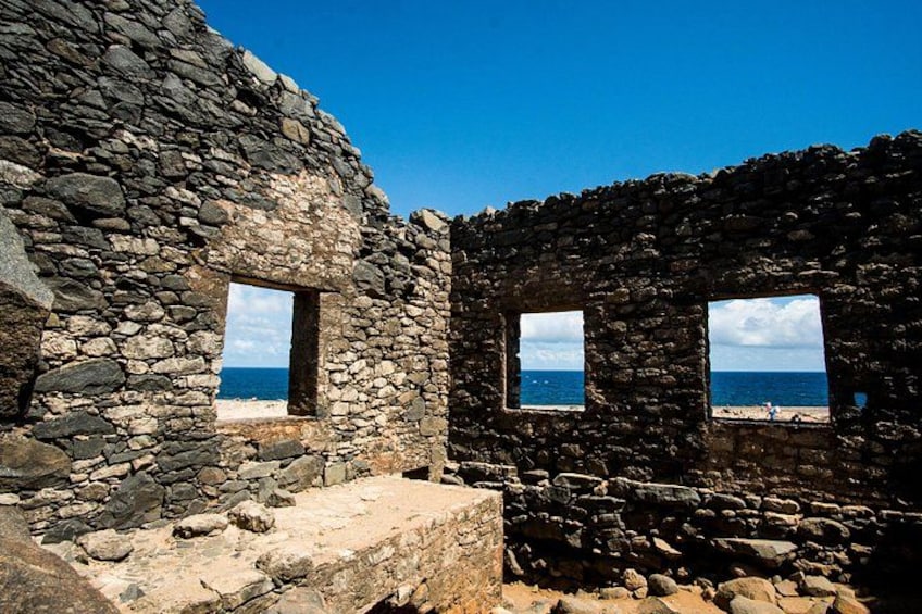 A stone building with two windows overlooking a beach. 4