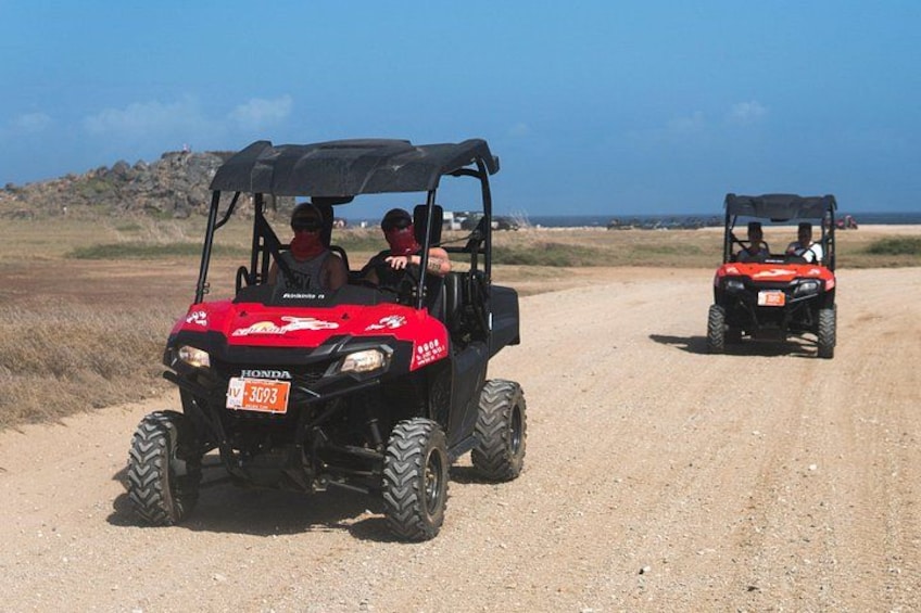 Two off-road vehicles on a dirt road with a clear sky and distant landscape. 1