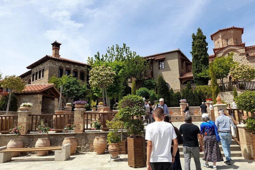 Un patio con edificios de piedra, plantas en macetas y un grupo de personas. 2