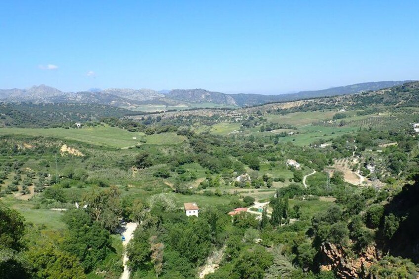 A valley with scattered houses, a winding road, and distant mountains. 2