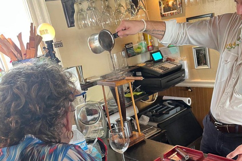 Eine Person gießt Flüssigkeit aus einer Karaffe in ein Glas. 2