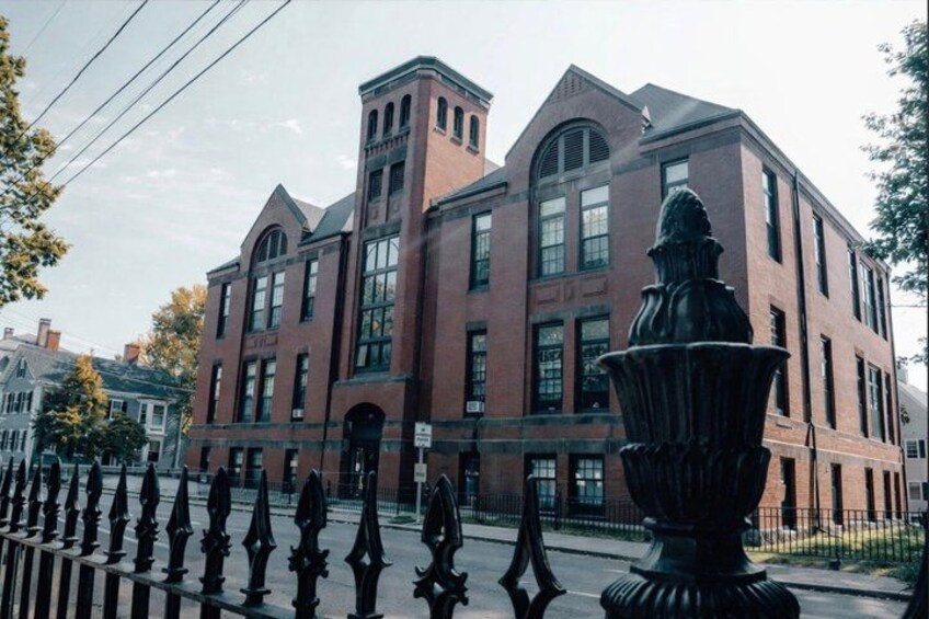 A red brick building with large windows and a decorative urn in the foreground. 3