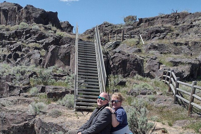 A wooden staircase leading up a rocky hill with sparse vegetation. 2