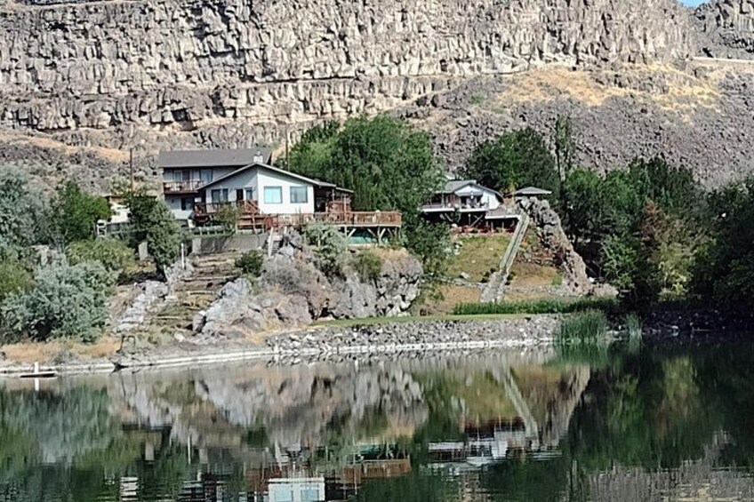 A house by a lake with a rocky hillside in the background. 3