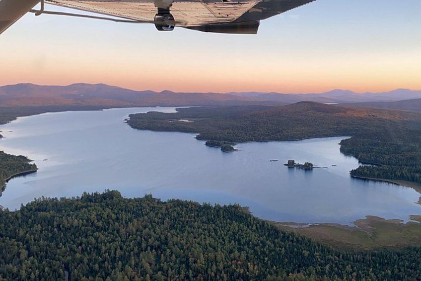 Un hélicoptère survole un lac entouré de collines boisées. 4