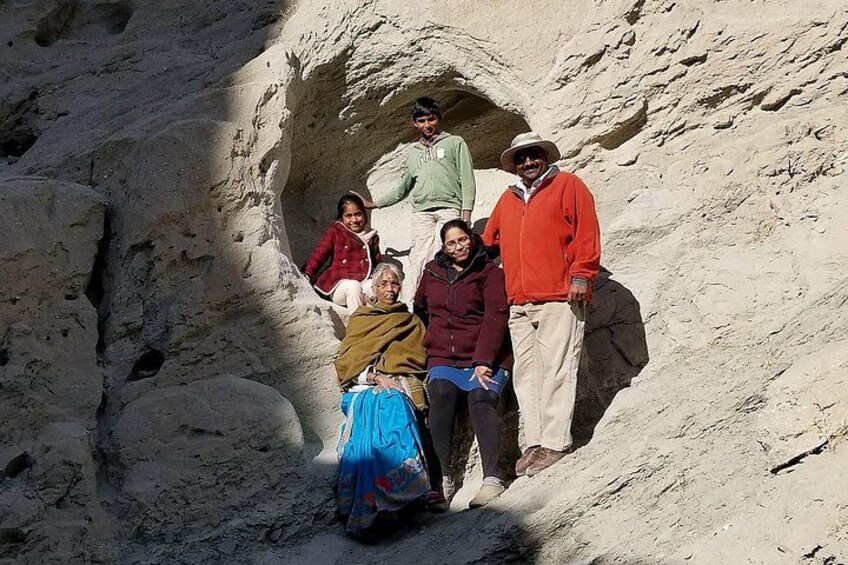 Un grupo de personas de pie sobre un terreno rocoso con una estructura similar a una cueva. 2